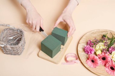 İşteki çiçekçi: kadın hasır sepet ve çiçekleri kullanarak nasıl şirin doğum günü hediyesi yapılacağını gösteriyor.