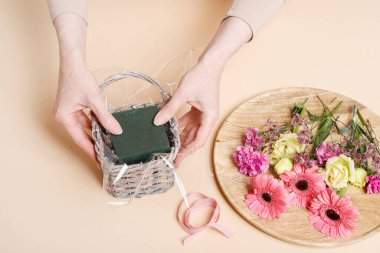 İşteki çiçekçi: kadın hasır sepet ve çiçekleri kullanarak nasıl şirin doğum günü hediyesi yapılacağını gösteriyor.