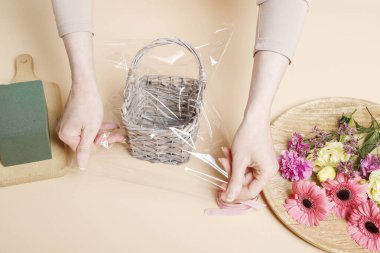 İşteki çiçekçi: kadın hasır sepet ve çiçekleri kullanarak nasıl şirin doğum günü hediyesi yapılacağını gösteriyor.