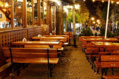 ZAKOPANE, POLAND - 24 Ekim 2024: Zakopane 'de Krupowki Caddesi' ndeki bir barda ahşap banklar ve masalar. Turistler için tatil yeri