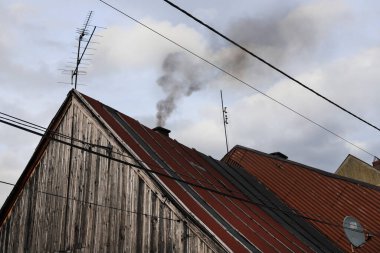 Ev fırınında yanan çöpten çıkan pis siyah duman evin bacasından çıkıyor. Sis kirliliği
