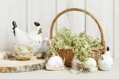 Seramik tavuk heykelcikleri, yumurtalar ve yeşil çiçeklerle şirin Paskalya süsleri. Şenlikli parti dekorasyonu
