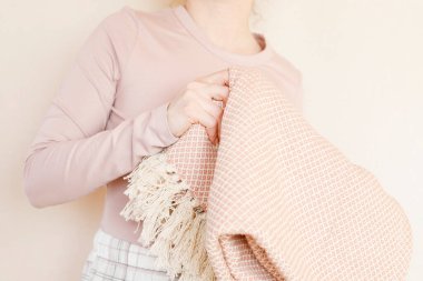 Genç bir kadın pembe yumuşak bir battaniye tutuyor. Uyku zamanı.