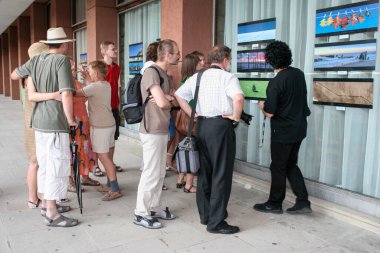 KRYNICA-ZDROJ, POLAND - Temmuz 09, 2006: Ulusal Doğa ve Peyzaj Fotoğrafları Festivali katılımcıları spa binasının pencerelerinde sunulan fotoğraflara bakıyorlar. Turistler için tatil yeri