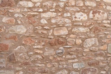 Old restored rustic fence - old stone wall with several shades of red and brown. Traditional Mediterranean method of building 
