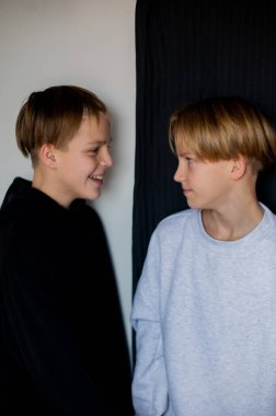 İki mutlu erkek kardeş, gerçekten mutlu bir birliktelikleri var. Kardeşler gri arka planda kalır. Modern tenajcılar. Kitap kapağı. Biri odakta, diğeri odakta değil.