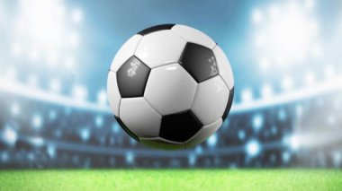 Havada dönen bir futbol topu var, aydınlık bir stadyumda.