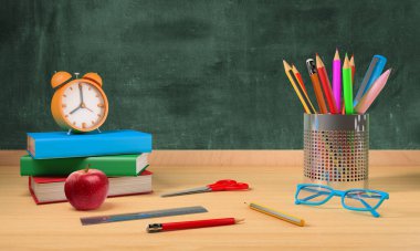 Okula dönmek için karatahta, kalem tutacağı, kitap ve aletleri olan bir masa.