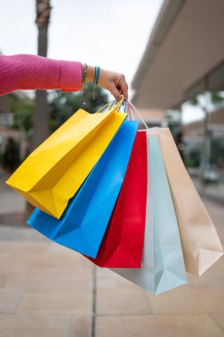 Alışveriş torbaları taşıyan kişi alışveriş merkezinde perakende terapinin keyfini çıkarıyor.