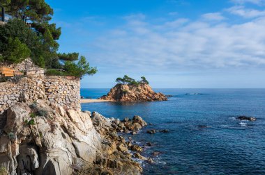 Akdeniz manzarası kayalık bir sahil şeridinde küçük bir adayı kucaklıyor.