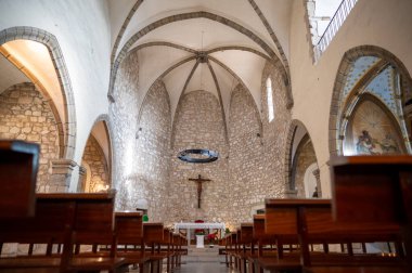 İçinde taş duvarlar, ahşap sıralar, yüksek tavan ve dini ikonografi bulunan boş bir kilise iç mimarisi, dinsel ve dinsel bir atmosfer yaratıyor.