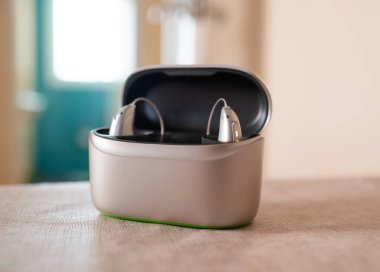 Bir çift işitme cihazı çantalarında şarj oluyor, daha iyi duyabilmek için modern teknolojiyi sergiliyorlar.