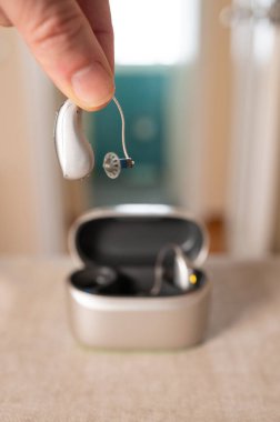 Doktor arka planda şarj ve kurutma davasında yeni işitme cihazı gösteriyor