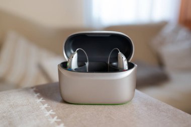 Modern işitme cihazları taşınabilir bir çantada şarj oluyor, daha iyi işitme ve aktif bir yaşam tarzı için teknolojiyi sergiliyor