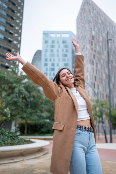 Счастливая предпринимательница, поднимающая оружие, празднующая успех бизнеса в современном финансовом районе города