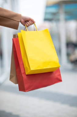 Alışveriş merkezinde yürürken alışveriş torbaları taşıyan bir kadın.