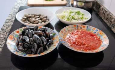 Taze midyeler, midyeler, doğranmış soğanlar ve domates sosu mutfak tezgahında pişirilmeye hazır.