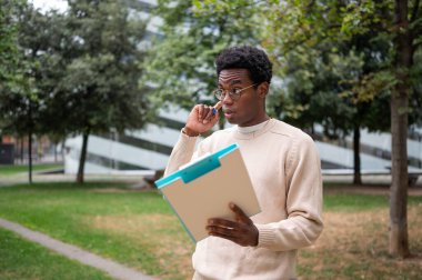 Düşünceli bina müfettişi dışarıdaki bir panoda belgeleri inceliyor.