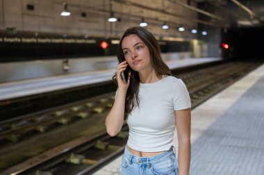 Treninin metro istasyonuna varmasını beklerken genç kadın bir telefon görüşmesi yapıyor.