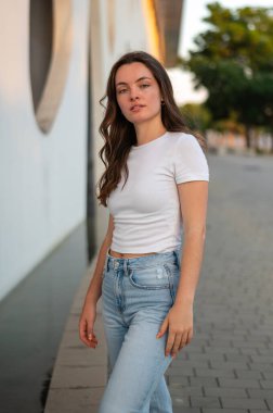 Şık bir genç kadın şehir ortamında kaldırımda yürüyor.