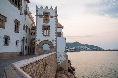 Beyazlaşmış siteler şafak vakti sakin balistik denize tepeden bakan kayalık sahilde duruyor.