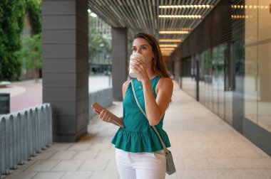 İş kadını elinde tabletle kahve molası verip modern şehir yaşam tarzını sergiliyor.