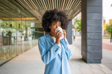 Young manager enjoying a coffee break outside her office building