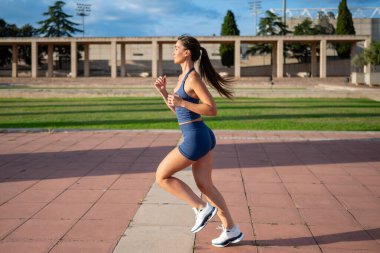 Young woman in sportswear jogging on an urban path, maintaining an active and healthy lifestyle