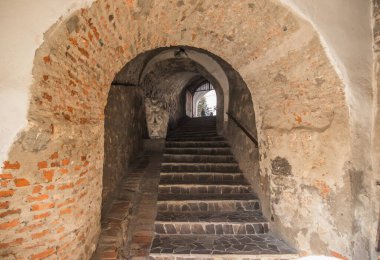 Eski şatonun iki parçası arasında eski bir taş merdiven var. Taş kemer ve kaleye adımlar. Eski şatoda merdivenleri olan taş koridor..