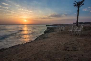 Denizde güzel bir gün doğumu. Kızıl Deniz 'de şafak vakti. Güneş, denize yansıyor. Mavi şafak gökyüzünde hafif bulutlar. Deniz kenarındaki güzel sandalyeler. Tropik gün doğumu