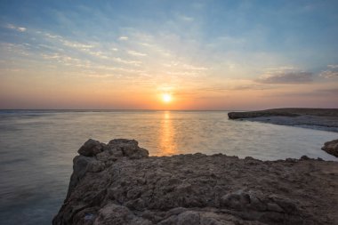 Denizde güzel bir gün doğumu. Kızıl Deniz 'de şafak vakti. Güneş, denize yansıyor. Mavi şafak gökyüzünde hafif bulutlar. Tropik gün doğumu. Uzun süre açık havada kalan düz deniz.