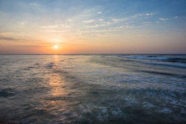 Denizde güzel bir gün doğumu. Kızıl Deniz 'de şafak vakti. Güneş, denize yansıyor. Mavi şafak gökyüzünde hafif bulutlar. Tropik gün doğumu.