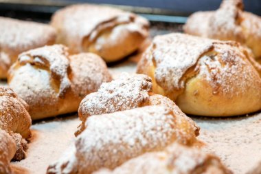 Sweet homemade croissants sprinkled with vanilla sugar. Small buns from the oven on a baking sheet. Delicious buns sprinkled with vanilla sugar