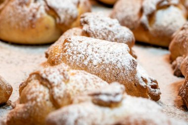 Sweet homemade croissants sprinkled with vanilla sugar. Small buns from the oven on a baking sheet. Delicious buns sprinkled with vanilla sugar