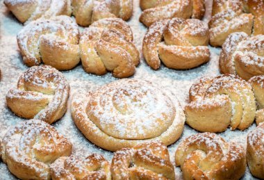 Sweet homemade cakes sprinkled with vanilla sugar. Small cookies from the oven on a baking sheet. Delicious cookies sprinkled with vanilla sugar