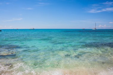 Caribbean beach with a lot of palms and white sand, Dominican Republic. Yachts float in the sea in the background