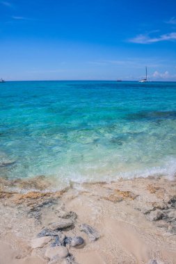 Caribbean beach with a lot of palms and white sand, Dominican Republic. Yachts float in the sea in the background