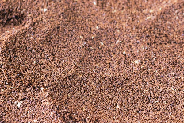 The grains of ground black coffee are very close. Close up ground coffee background. Brown coffee powder texture extreme closeup photo