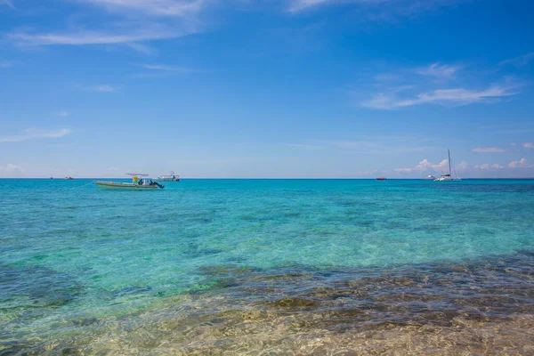 Caribbean beach with a lot of palms and white sand, Dominican Republic. Yachts float in the sea in the background