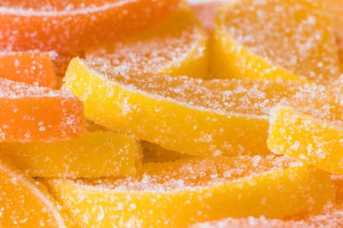 Turuncu ve sarı marmelatlı şekerlemelerin dekoratif arkaplanı turunçgil meyvesi şeklinde. Jöleli şeker. Yemek dokusu. Güzel kare duvar kağıdı veya Web afişi.