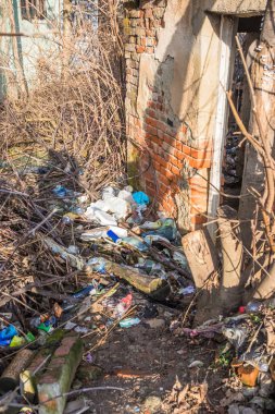 Eski evin yakınındaki plastik şişeler ve çöpler. Kullanılmış kirli plastik şişeler. Çevre kirliliği. Ekolojik bir sorun. Eski evin yakınındaki çöplükte.