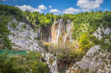 Plitvice Gölleri 'ndeki güzel şelalelerin manzarası. Mavi suyu olan göllerin etrafındaki kayalar ve yeşil ağaçlar. Hırvatistan 'daki Plitvice Gölleri Ulusal Parkı nefes kesici bir manzara.