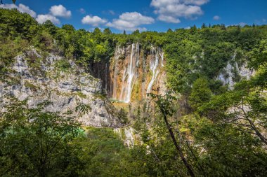 Plitvice Gölleri 'ndeki güzel şelalelerin manzarası. Mavi suyu olan göllerin etrafındaki kayalar ve yeşil ağaçlar. Hırvatistan 'daki Plitvice Gölleri Ulusal Parkı nefes kesici bir manzara.