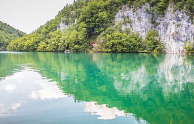 Güzel, berrak mavi Plitvice Gölleri manzarası. Mavi suyu olan göllerin etrafındaki kayalar ve yeşil ağaçlar. Hırvatistan 'daki Plitvice Gölleri Ulusal Parkı nefes kesici bir manzara.