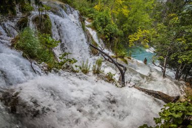 Plitvice Gölleri 'ndeki güzel şelalelerin manzarası. Mavi suyu olan göllerin etrafındaki kayalar ve yeşil ağaçlar. Hırvatistan 'daki Plitvice Gölleri Ulusal Parkı nefes kesici bir manzara.