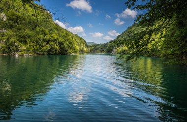 Güzel, berrak mavi Plitvice Gölleri manzarası. Mavi suyu olan göllerin etrafındaki kayalar ve yeşil ağaçlar. Hırvatistan 'daki Plitvice Gölleri Ulusal Parkı nefes kesici bir manzara.