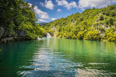 Güzel, berrak mavi Plitvice Gölleri ve pitoresk şelalelerin manzarası. Mavi suyu olan göllerin etrafındaki kayalar ve yeşil ağaçlar. Hırvatistan 'daki Plitvice Gölleri Ulusal Parkı nefes kesici bir manzara.