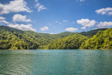 Güzel, berrak mavi Plitvice Gölleri manzarası. Mavi suyu olan göllerin etrafındaki kayalar ve yeşil ağaçlar. Hırvatistan 'daki Plitvice Gölleri Ulusal Parkı nefes kesici bir manzara.