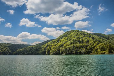 Güzel, berrak mavi Plitvice Gölleri manzarası. Mavi suyu olan göllerin etrafındaki kayalar ve yeşil ağaçlar. Hırvatistan 'daki Plitvice Gölleri Ulusal Parkı nefes kesici bir manzara.