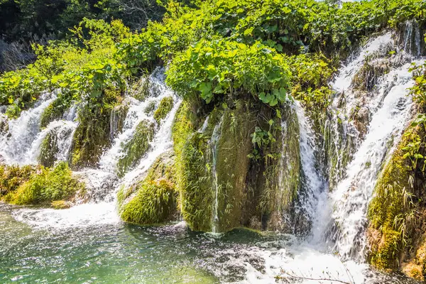 Plitvice Gölleri 'ndeki güzel şelalelerin manzarası. Mavi suyu olan göllerin etrafındaki kayalar ve yeşil ağaçlar. Hırvatistan 'daki Plitvice Gölleri Ulusal Parkı nefes kesici bir manzara.